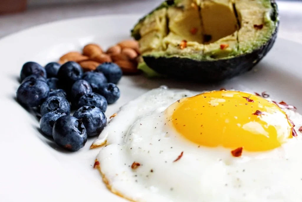 Blaubeeren, ein Spiegelei, eine Avocado und Nüsse auf einem Teller