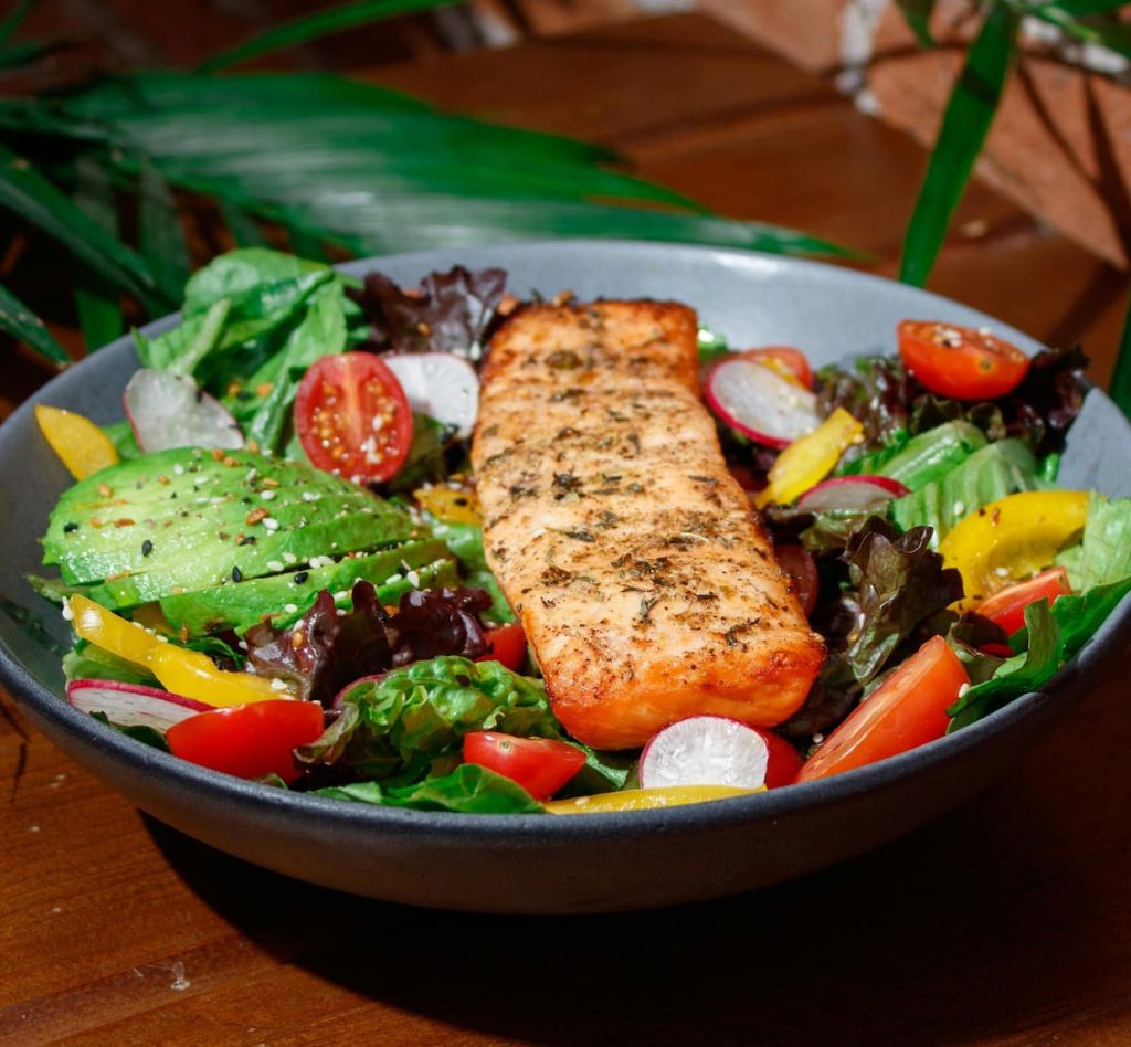 Gericht mit gebratenem Lachs, Salat, Avocado, Sesam
