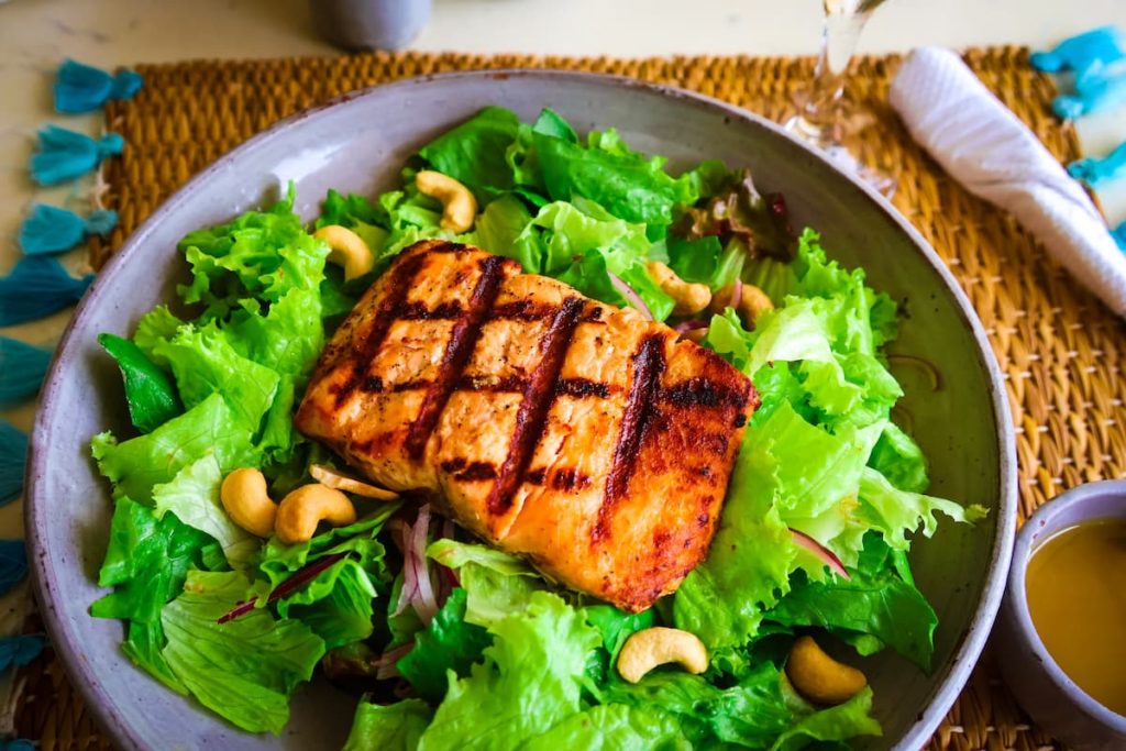 Gericht mit gebratenem Lachs, Cashewnüssen, Salat, Zwiebeln